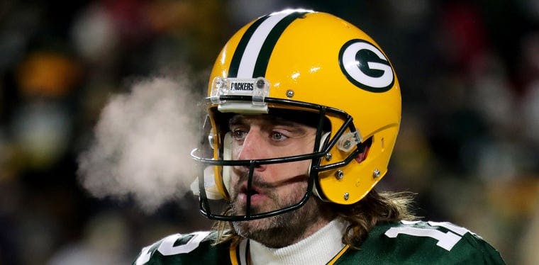 Aaron Rodgers takes a look at the field in Green Bay during a 2022 NFL Playoff contest.