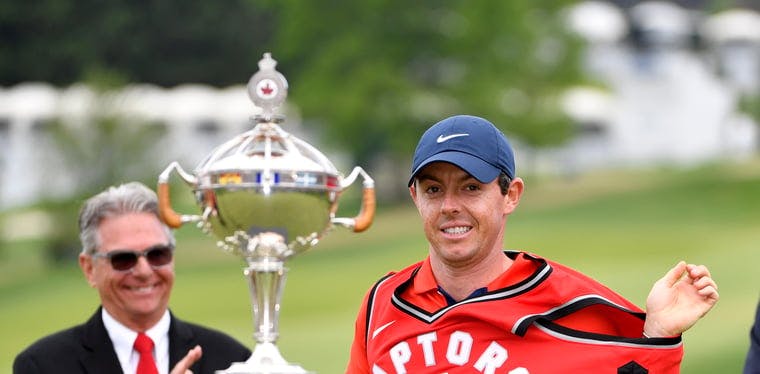 Rory McIlroy wears a Toronto Raptors jersey and poses with the trophy after winning the 2019 RBC Canadian Open