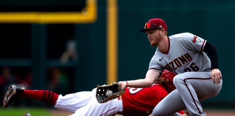 Reds left fielder TJ Friedl dives back to first as Diamondbacks right fielder Pavin Smith  receives an attempted pick off throw