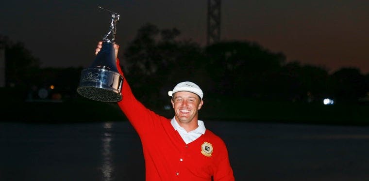 Bryson Dechambeau holds up the 2021 Arnold Palmer Invitational trophy in the red sweater also given out by the Arnold Palmer Invitational.