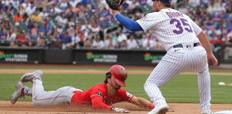 Reds shortstop Kyle Farmer slides into third base with a triple in front of New York Mets third baseman Brandon Drury