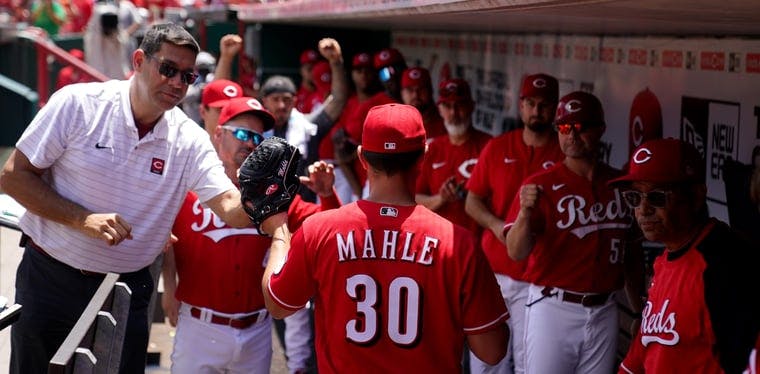 Reds players celebrate in the dugout with Tyler Mahle