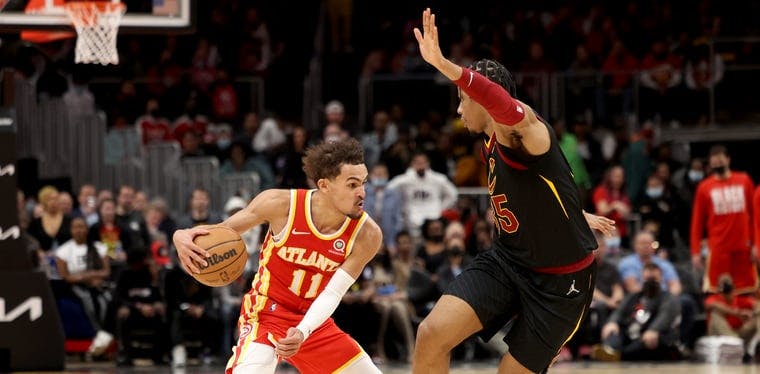 Hawks guard Trae Young (11) performs a crossover dribble on Cavs guard/forward Isaac Okoro (35) in a February 2022 NBA contest from Atlanta.
