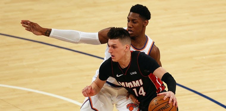 Heat guard Tyler Herro (14 in the black uniform) is tightly guarded by Knicks guard RJ Barrett (on Herro's right) in an 2021 contest between the New York Knicks and Miami Heat. 