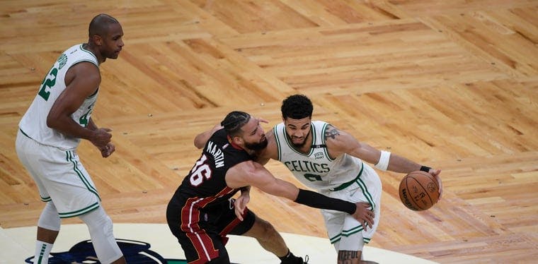 Celtics forward Jayson Tatum drives down the court defended by Miami Heat forward Caleb Martin