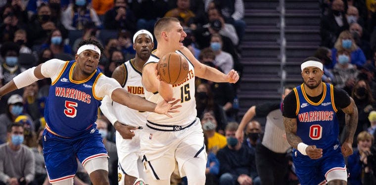Warriors' Kevon Looney attempts to steal the ball from Nuggets center Nikola Jokic in a December 2021 contest