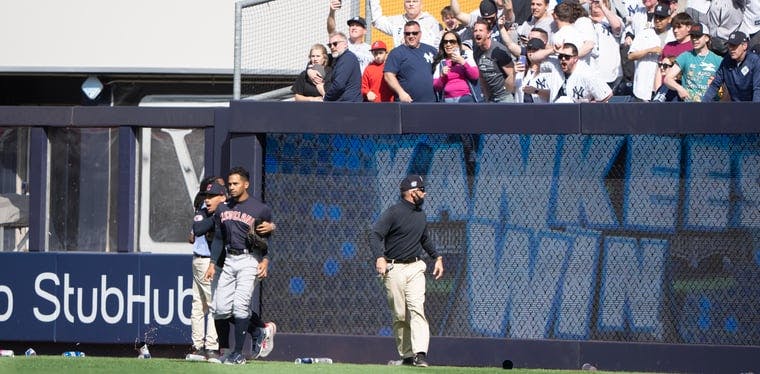 Guardians outfielder Oscar Mercado walks away from fans as they throw beer cans and water bottles at him after the Yankees beat the Guardians