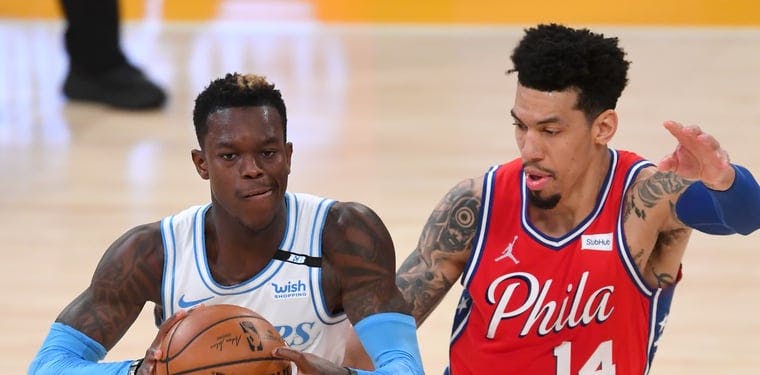 Dennis Schröder (in white and blue) looks to pass the ball in a 2021 matchup against Danny Green (14 in red) and the Philadelphia 76ers